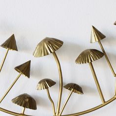 brass mushrooms are arranged on a white surface, with one standing out from the others