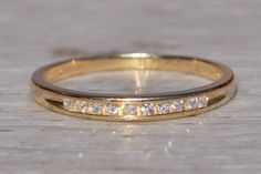 a yellow gold wedding band with five diamonds on it, sitting on a wooden surface