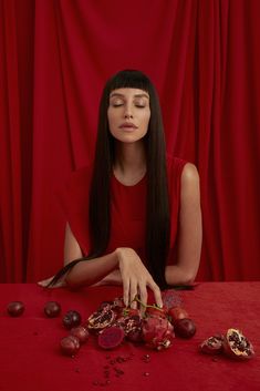 a woman sitting at a table with fruit on it