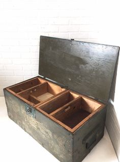 an old wooden box with two open compartments sitting on a white floor next to a brick wall