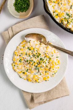 a white plate topped with macaroni and cheese next to a bowl of chives