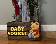 there is a wooden box with clothes hanging on it and a baby voggi sign