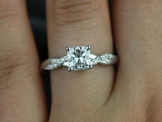 a woman's hand with a diamond ring on top of her finger and an engagement band