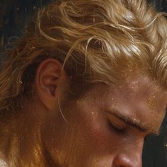 a close up of a person with gold paint on his face and hair blowing in the wind