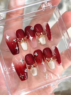 red and white nails with gold accents on the tip of each nail are displayed in a clear case