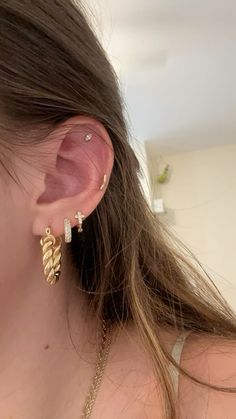 a close up of a person wearing gold ear cuffs and earrings with leaves on them