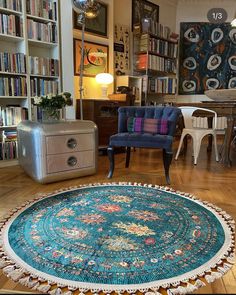 a living room filled with furniture and bookshelves next to a blue rug on top of a hard wood floor