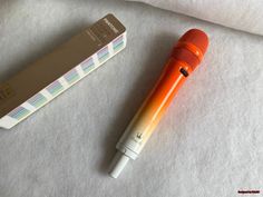 an orange and white microphone sitting next to a box on top of a sheet of paper