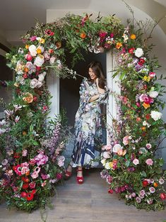 a woman standing in front of a doorway surrounded by flowers