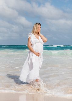 a pregnant woman standing in the water at the beach