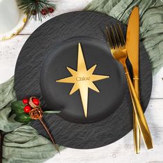 a black plate with a gold star on it next to a silver fork and knife