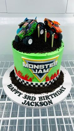 a monster truck themed birthday cake on top of a cooling rack in a refrigerator with frosting