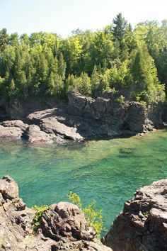 a man standing on top of a cliff next to a river filled with green water