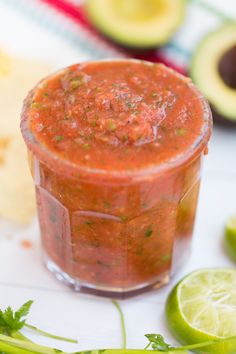 a small glass container filled with salsa next to sliced limes