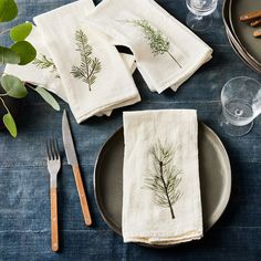 four napkins with herbs on them are sitting on a table next to silverware and utensils