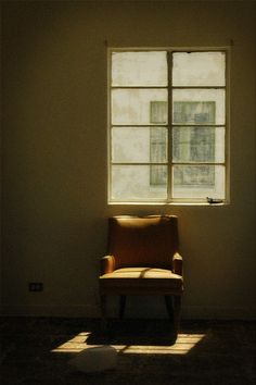 a chair sitting in front of a window with the sun shining through it's windows