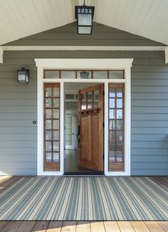 the front door of a house with two lanterns on it's roof and wooden decking