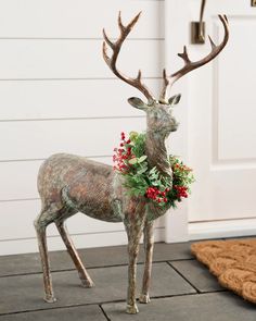 a statue of a deer with flowers on its antlers stands in front of a door