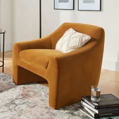 an orange chair sitting on top of a rug in a living room next to a lamp