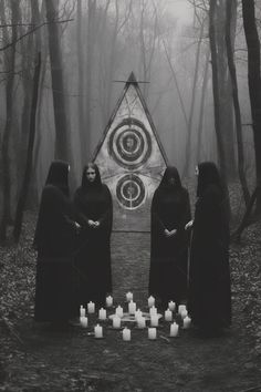 three women standing in front of a triangle surrounded by candles