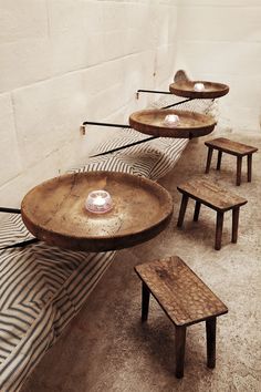 several wooden tables and stools are arranged in a row on the floor next to a brick wall