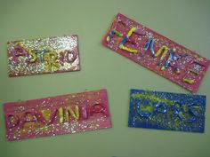 three pink and one blue name tags with glitter on them