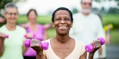 a woman holding two pink dumbs in front of her and several other people behind her