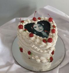 a heart shaped cake with cherries on the edges and a photo in the middle