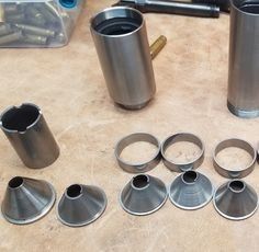 there are many metal objects on the table together, including cups and wrenches