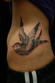 a woman's stomach with a bird tattoo on it