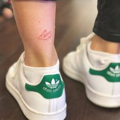 a woman's foot with a small green and white adidas logo on it