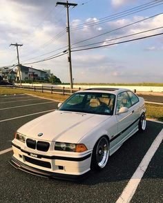 a white car parked in a parking lot next to power lines