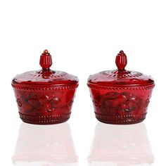 two red glass covered dishes sitting on top of each other