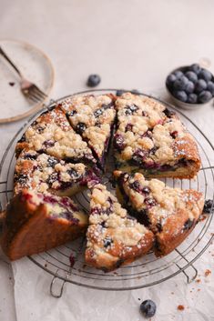 a blueberry crumb cake on a wire rack with two slices cut from it