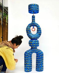 a woman kneeling down next to a blue sculpture with circles on it's sides