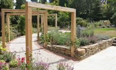 an outdoor garden area with stone walls and wooden pergols, surrounded by flowers