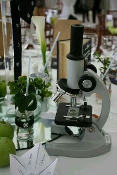 a table topped with lots of green apples next to a microscope and some paper boats