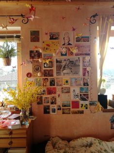 a bedroom with many pictures on the wall and flowers in vases next to it