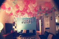 a living room filled with lots of balloons floating from the ceiling over a couch and tv