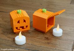 two lego pumpkin shaped candles sitting on top of a wooden table