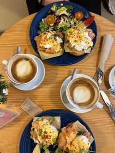 two blue plates topped with food next to cups of coffee