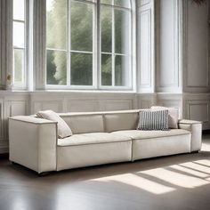 a white couch sitting in front of two windows