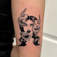 a woman's face with horns and demon eyes on her arm, done in black ink