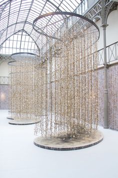 an art installation in the middle of a building with lots of white beads hanging from it's ceiling