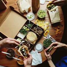 several people are eating sandwiches and salads at a table