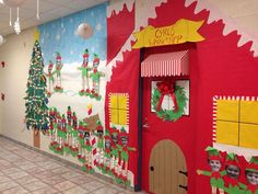 a hallway decorated for christmas with decorations on the wall and door, along with santa's workshop