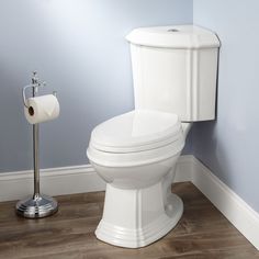 a white toilet sitting in a bathroom next to a roll of toilet paper on the floor