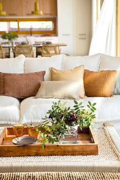 a living room with white couches and wooden tray on the coffee table in front of it