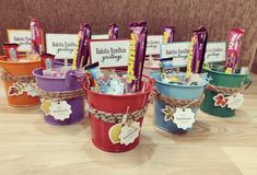 several colorful buckets filled with candy sitting on top of a wooden table next to each other