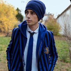 a young man wearing a blue and white striped jacket with a tie on his neck